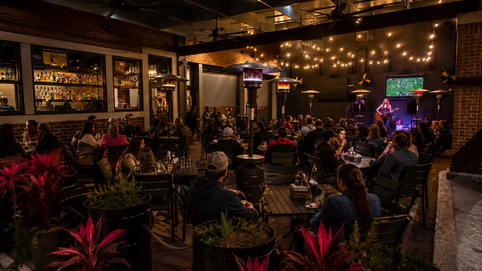 The patio at The Fillin' Station under string lights, tables full and a musician playing.